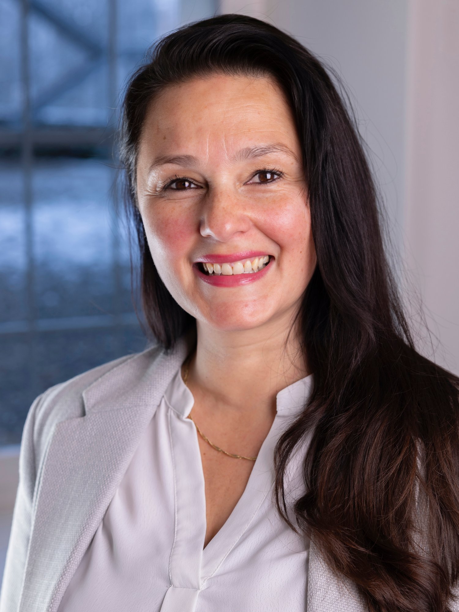 A woman in light blouse smiles to camera.